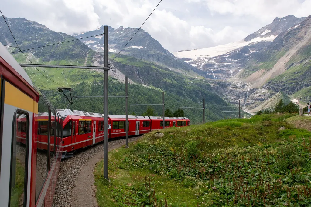 Ein roter Zug in der Kurve bei Alp Grüm, im Hintergrund der Palügletscher