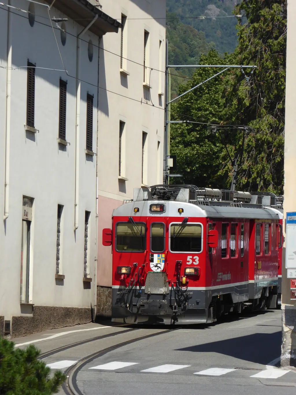 Ein roter Triebwagen der Berninabahn fährt mitten auf der Straße durch Tirano