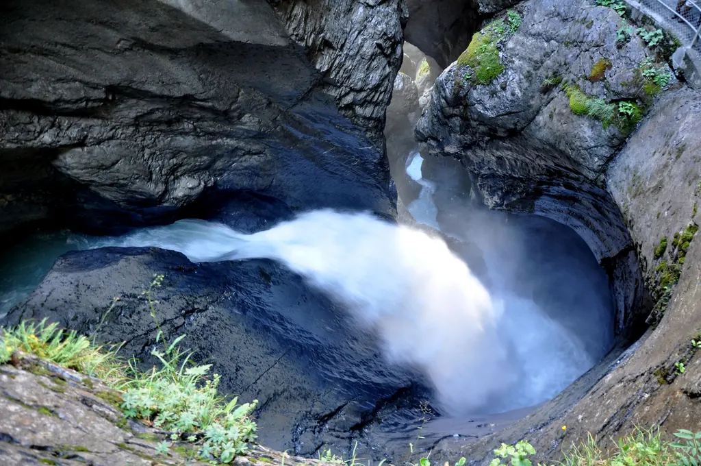 Im Inneren der Trümmelbachschlucht schießt weißes Gletscherwasser durch ein vom Wasser rund geschliffenes Felsbecken