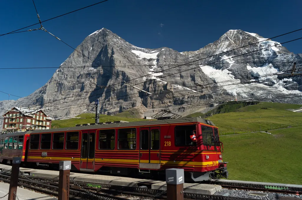 Ein roter Triebwagen der Jungfraubahn im Bahnhof Kleine Scheidegg, dahinter Eiger und Mönch