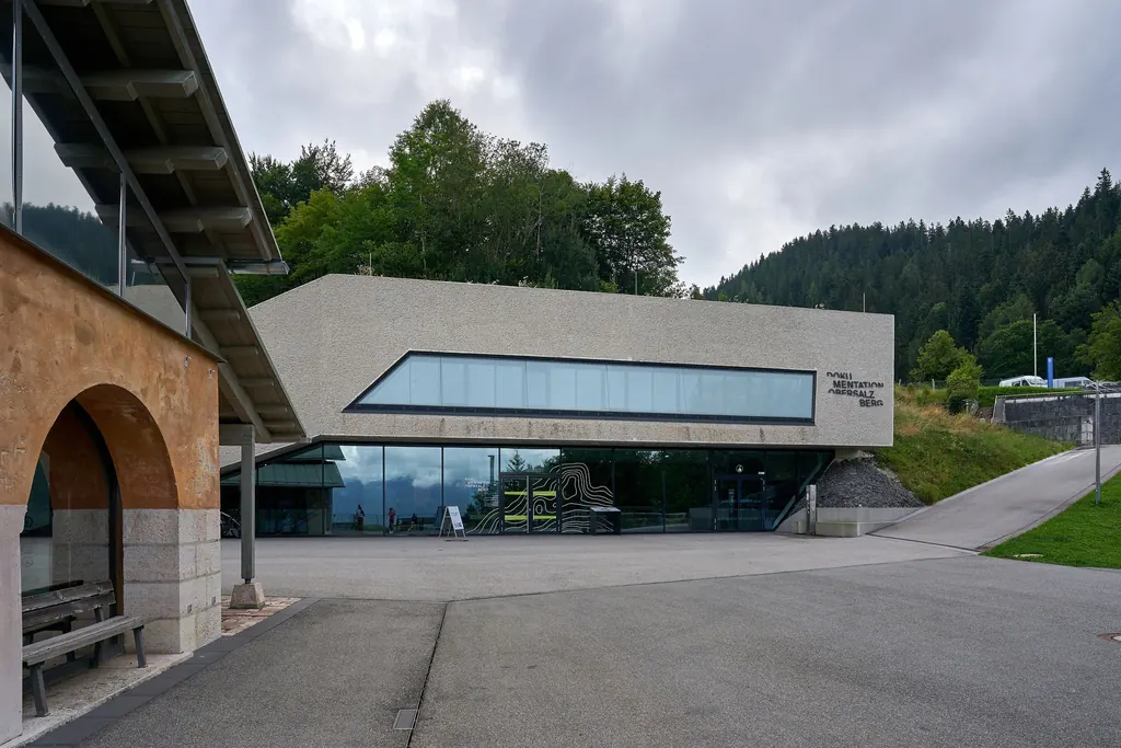 Der flache Betonneubau der Dokumentation Obersalzberg mit langem Fensterband, davor ein leerer Vorplatz unter grauem Himmel
