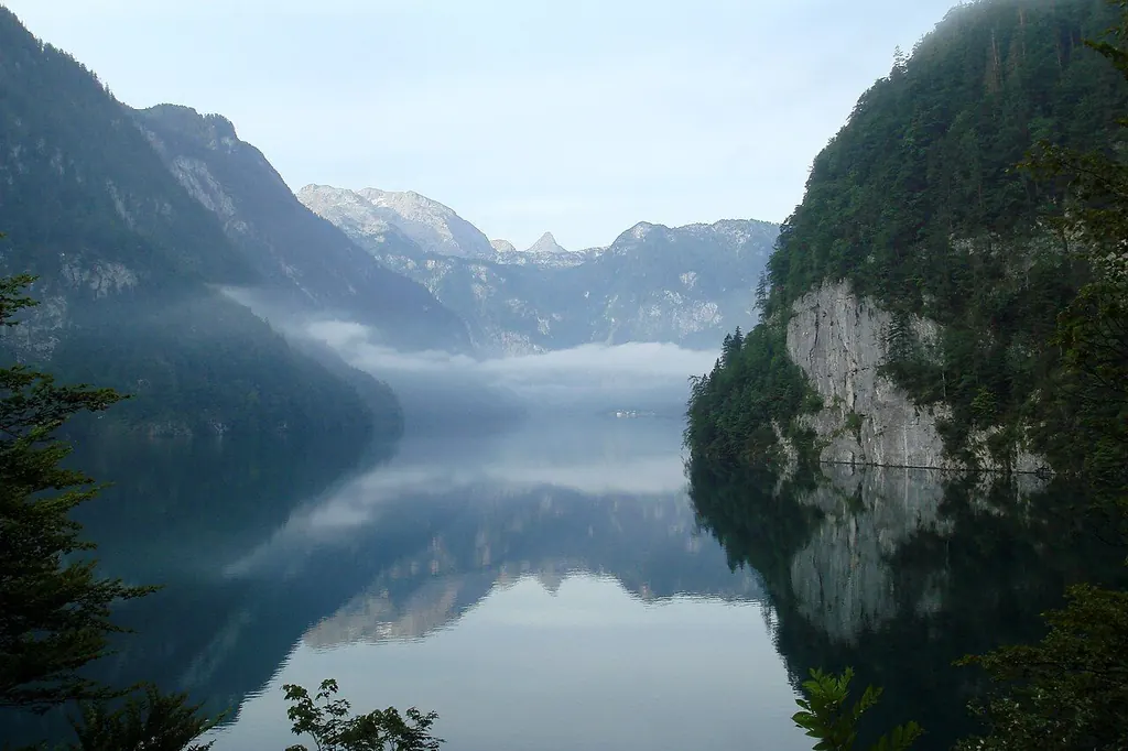 Der Königssee im Morgendunst, die Berge spiegeln sich im Wasser