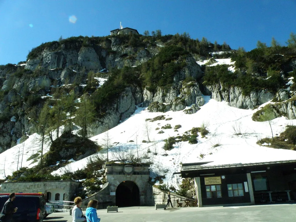 The stone tunnel portal at the Kehlstein car park, above it rock, snowfields and at the very top the Eagle's Nest