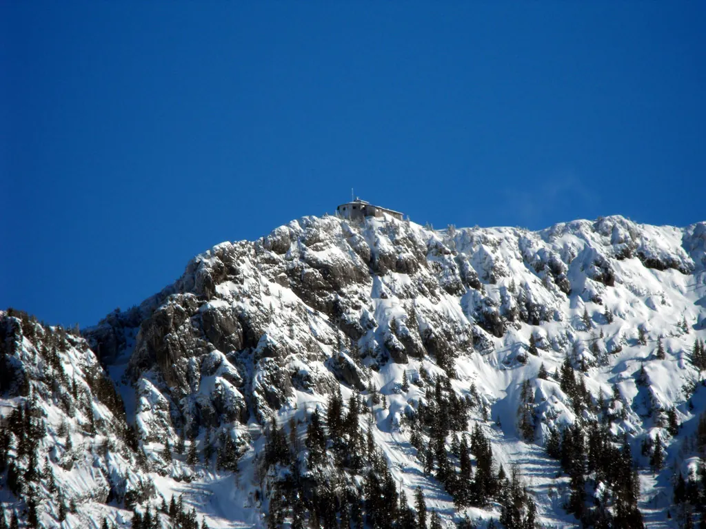 The Kehlstein deep in snow under a dark blue sky, the Eagle's Nest small at the very top of the ridge