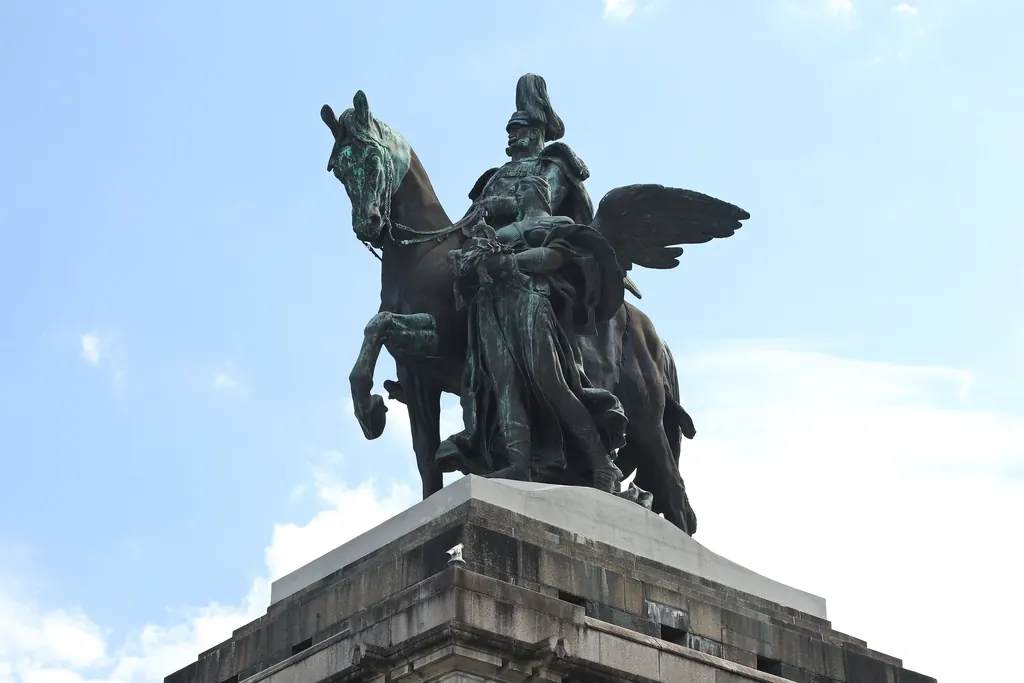 Das bronzefarbene Reiterstandbild Kaiser Wilhelms I. mit dem geflügelten Genius, von unten gegen den blauen Himmel fotografiert