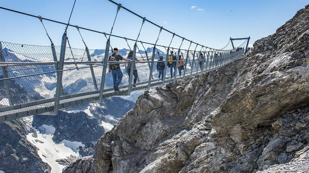 Menschen gehen über die Hängebrücke Titlis Cliff Walk, die zwischen Felswänden über einen Abgrund gespannt ist